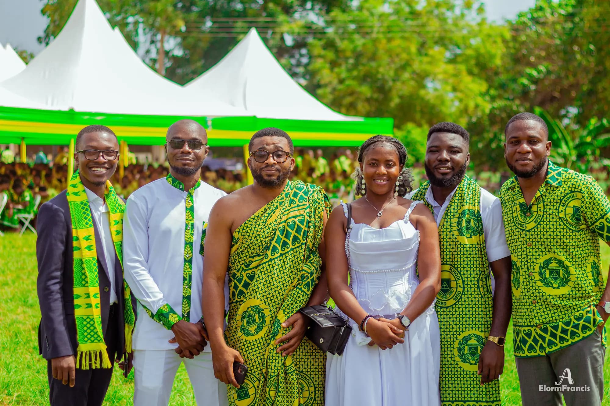 Alumni dressed in green and gold print posing together